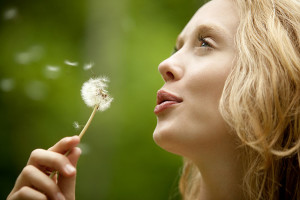 Young Woman blowing dandelion